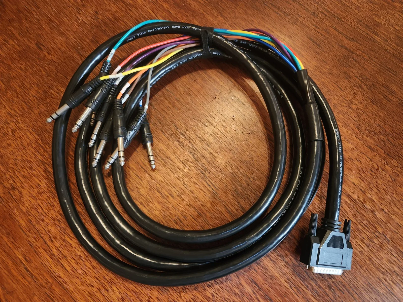 Photo of a DB25-to-TRS snake cable, showing the 25-pin D-Sub connector on one end fanning out into multiple individual TRS quarter-inch plugs.