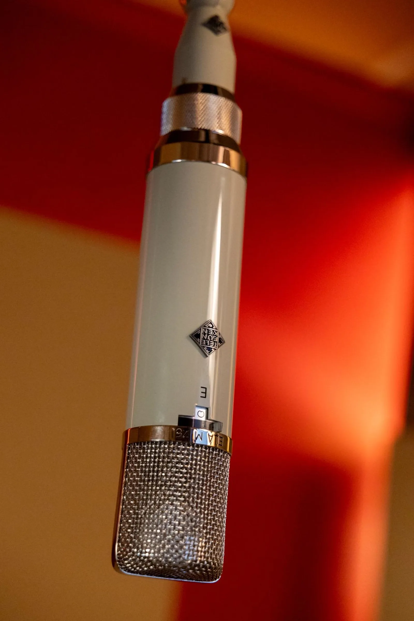 Photo of a Telefunken ELA M 251 large-diaphragm tube condenser microphone, showing its elongated cylindrical body with mesh capsule head and vintage styling.