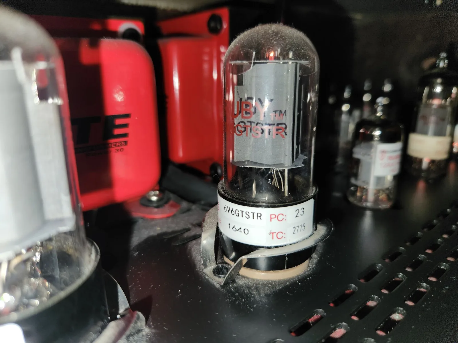 Photo of multiple vacuum tubes glowing orange inside an open tube saturation unit, with the internal circuitry visible.