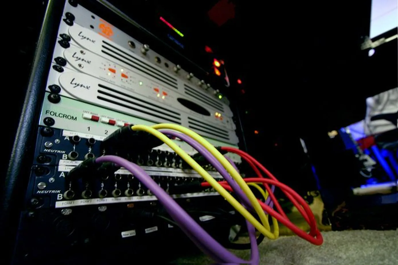 Photo of a Folcrom summing mixer front panel with multiple TRS patch cables inserted into its quarter-inch jacks in a studio rack.